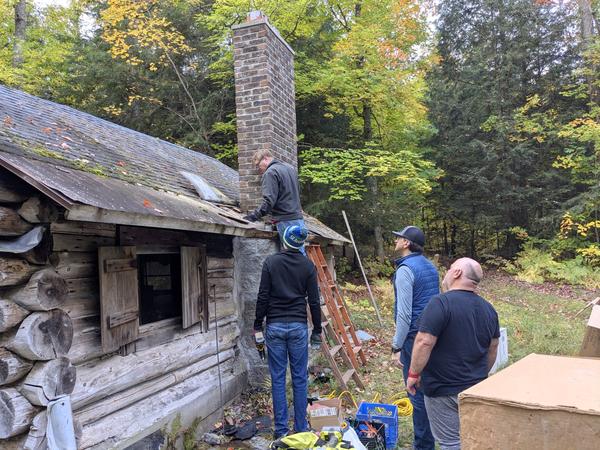 Bill cleaning out more of the old roof with Ed, Mikey, and Jon "supervising".