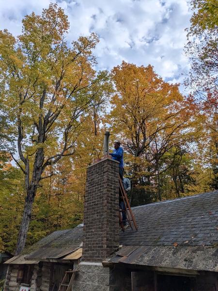 Bill adjusting the height of the flue pipe as the insert is trying to be put into the firebox.