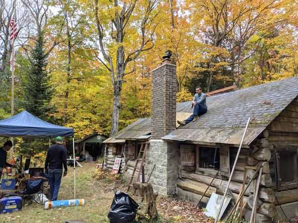 Mikey on the roof with a dry fit of the saddle he built to protect the chimney.
