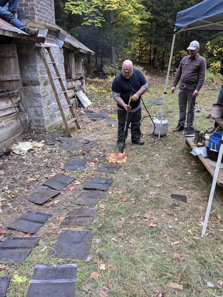 Jon heating shingles to cap the roof saddle.